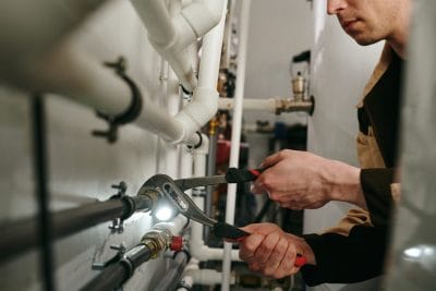 Technician inspecting commercial plumbing pipes in San Bruno