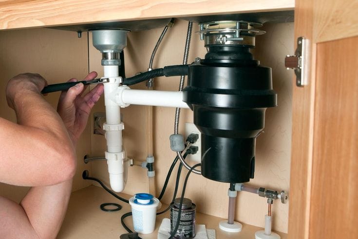 Plumber repairing a garbage disposal in San Bruno